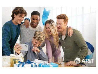 Five friends smiling together while taking a group selfie with a smartphone over wrapped holiday gifts