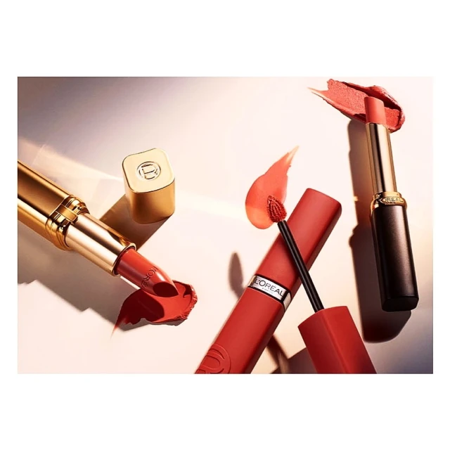 Cosmetic still life featuring lipstick tubes and applicators in warm coral tones, set against a soft gradient backdrop.