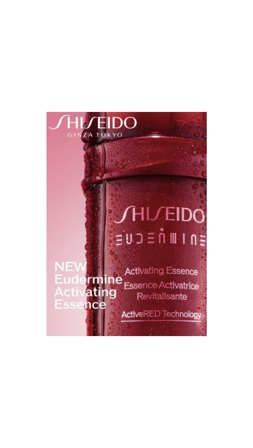 Close-up studio shot of Shiseido Eudermine activating essence, in a red bottle with water droplets, against a pink background.