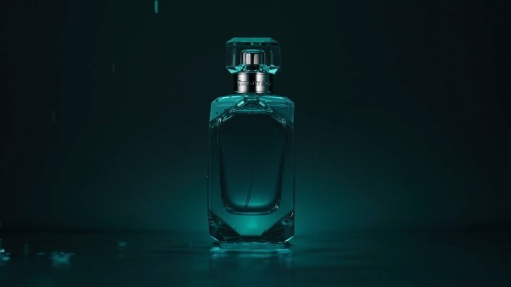 A product shot of a Tiffany & Co. perfume bottle with a crystal cap, set against a dark teal background with subtle lighting.