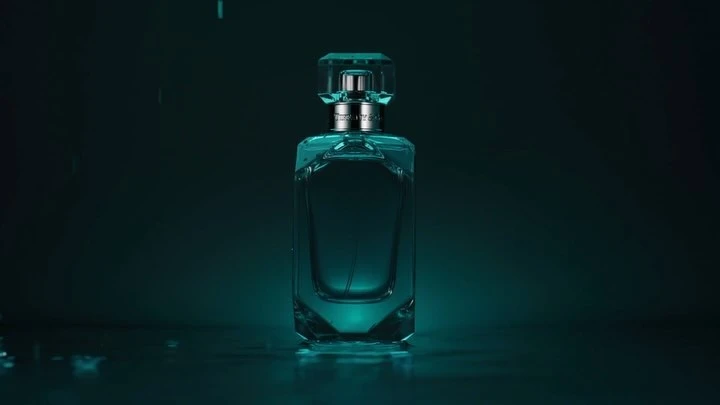 A product shot of a Tiffany & Co. perfume bottle with a crystal cap, set against a dark teal background with subtle lighting.