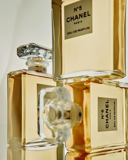Close-up studio shot of Chanel No. 5 Eau de Parfum bottles stacked with crystal caps on a white background, showcasing luxury beauty products.