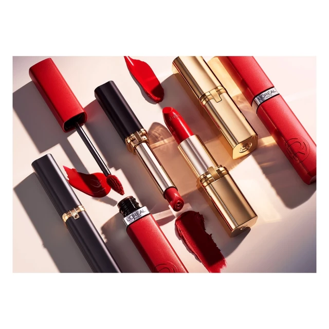 A collection of L'Oreal lipsticks in red, gold, and black packaging displayed in an overhead product shot with various lipstick swatches.
