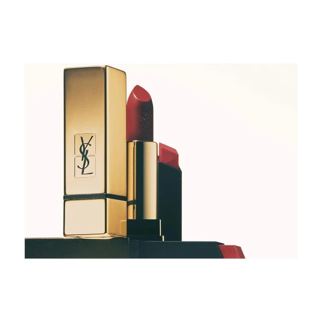 Close-up of a gold and red YSL lipstick tube, standing upright against a white backdrop, showcasing luxury cosmetics.