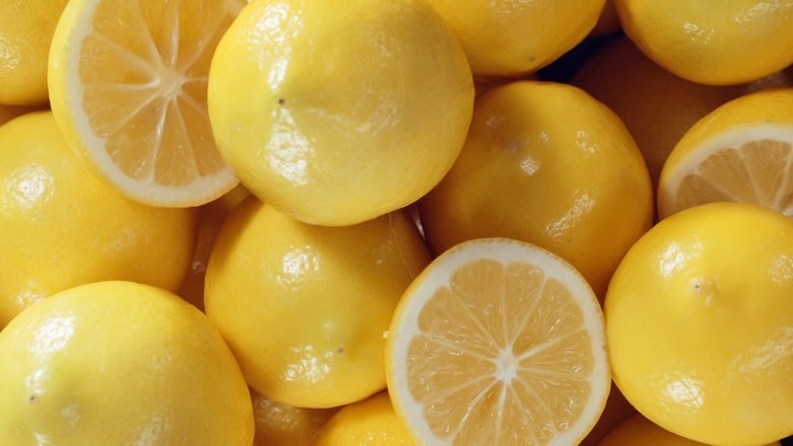 Close-up of many yellow lemons and lemon slices arranged together, creating a vibrant and fresh composition.