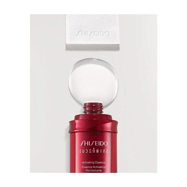 Still life of a red Shiseido Eudermine Revitalizing Essence bottle with a clear orb on top and a white cleansing cotton square.