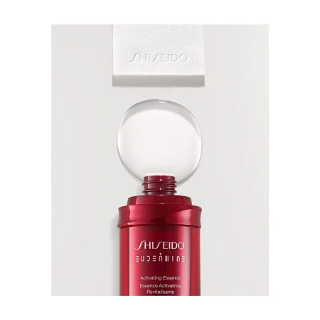Still life of a red Shiseido Eudermine Revitalizing Essence bottle with a clear orb on top and a white cleansing cotton square.