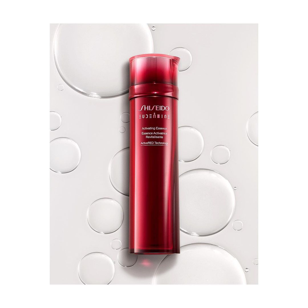 Red bottle of Shiseido Eudermine activating essence on white with water droplets. Beauty product for skincare and cosmetic use.