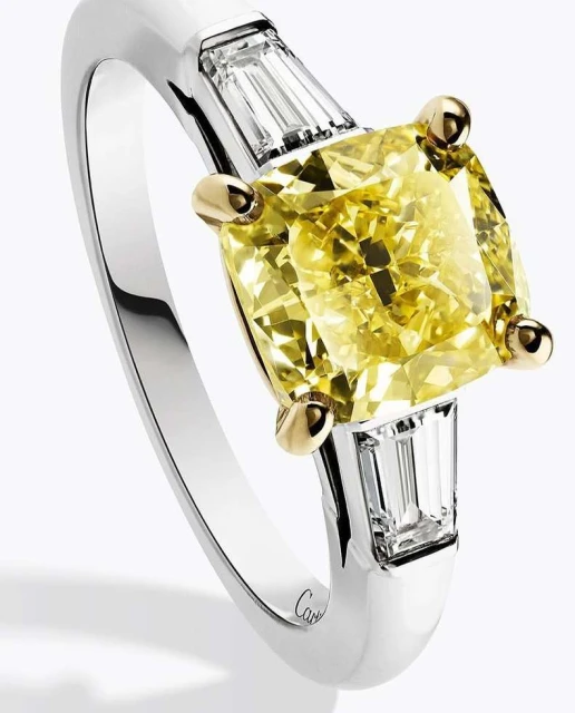 Close-up of a gemstone ring featuring a large cushion-cut yellow diamond flanked by baguette-cut diamonds set in a white gold band.