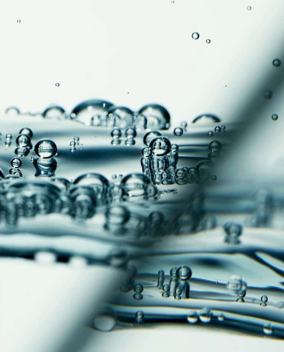 Close-up of water bubbles with a clear, transparent appearance, featuring a narrow depth of field and a soft, diffused light source.