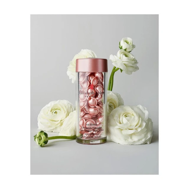 Elizabeth Arden Retinol Ceramide capsules in a clear container surrounded by white flowers on a neutral background in studio light.