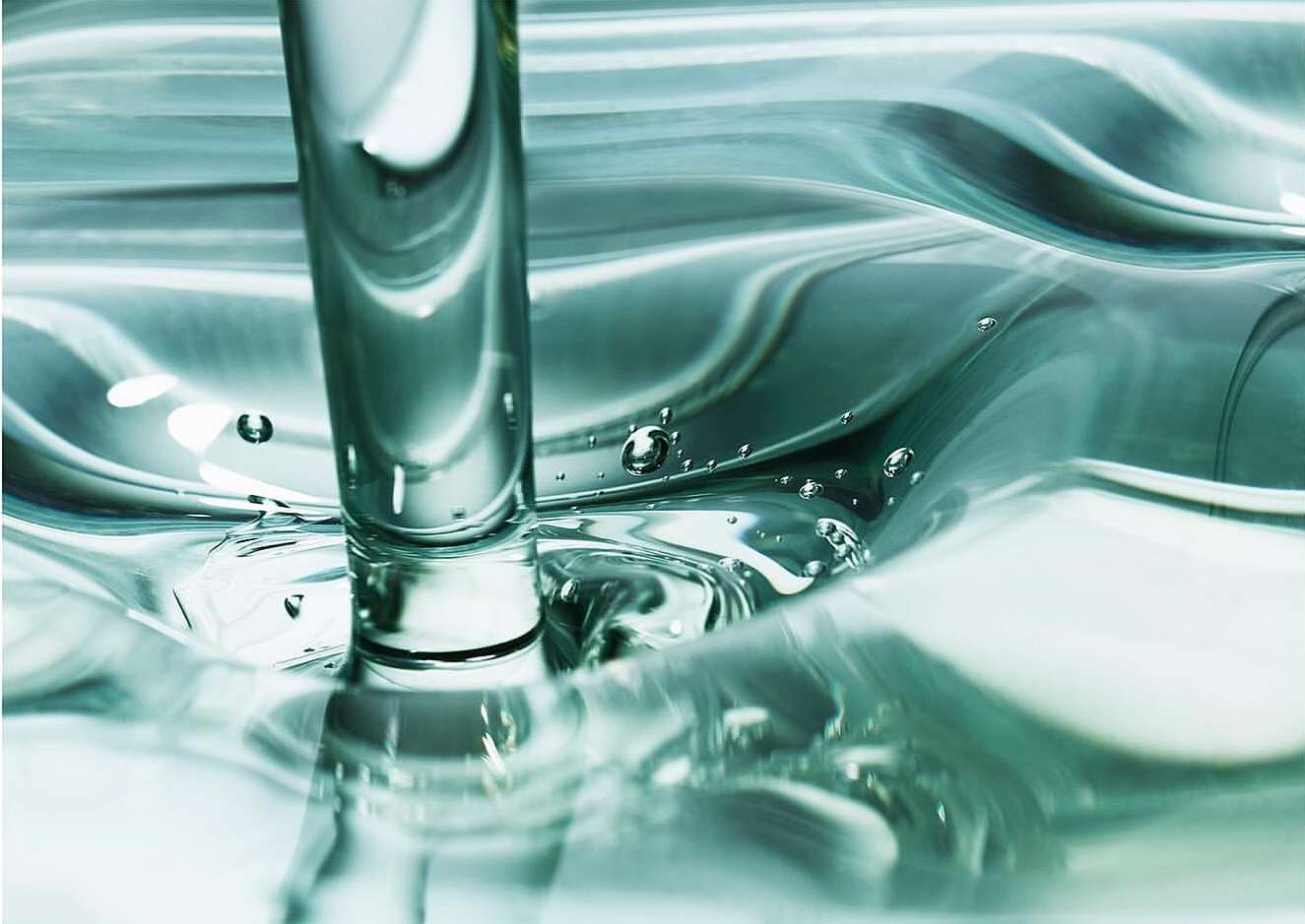 Close-up of a clear liquid, possibly water, being poured or flowing into a container, creating ripples and bubbles.