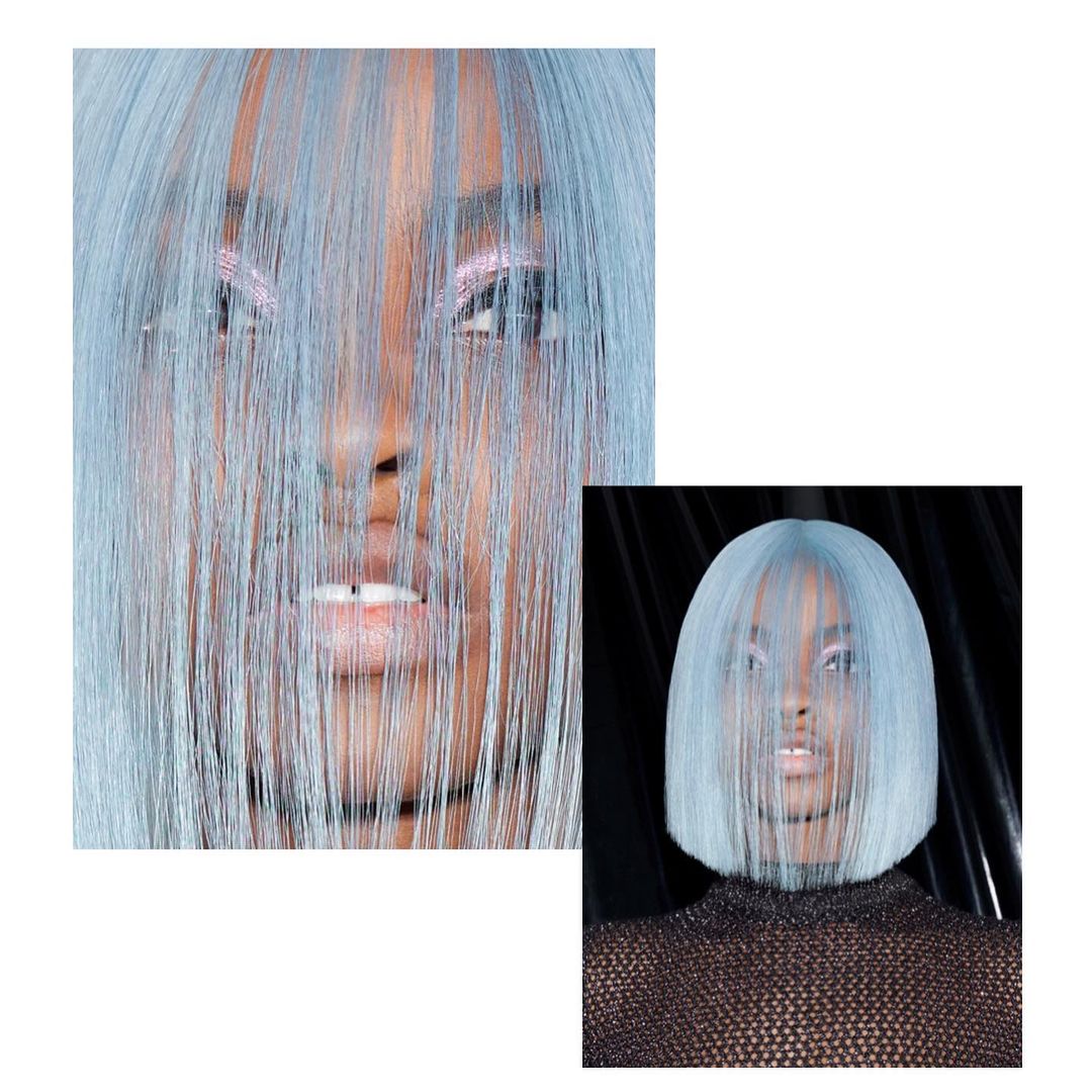 Close-up of a woman with light blue hair partially covering her face in a beauty shot, focusing on hair color and makeup.