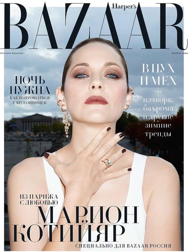 Magazine cover featuring Marion Cotillard wearing a white top and jewelry, posing indoors against a blurry outdoor background.