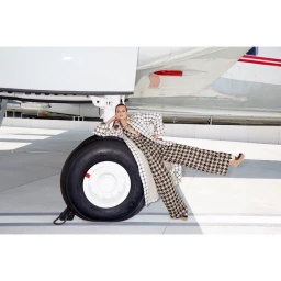Model in houndstooth jumpsuit leaning against an airplane tire photographed by Claire Rothstein