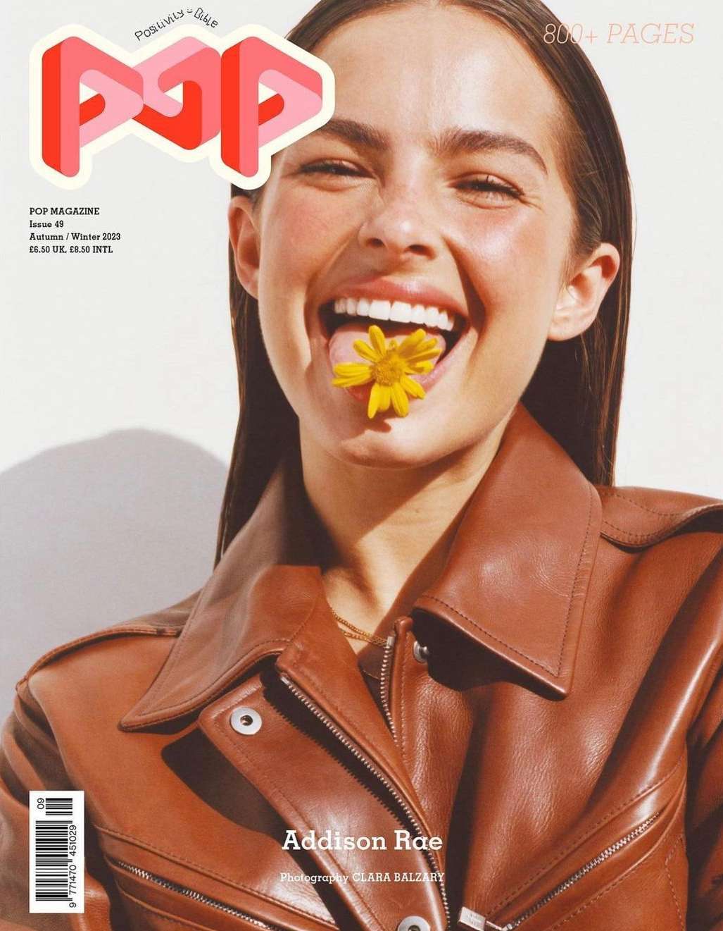 Addison Rae cover for POP magazine featuring a model with brown hair wearing a brown leather jacket and yellow flower in her mouth.