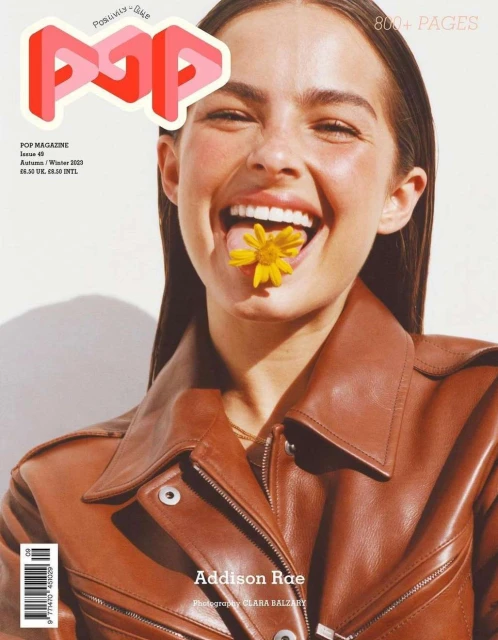 Addison Rae cover for POP magazine featuring a model with brown hair wearing a brown leather jacket and yellow flower in her mouth.
