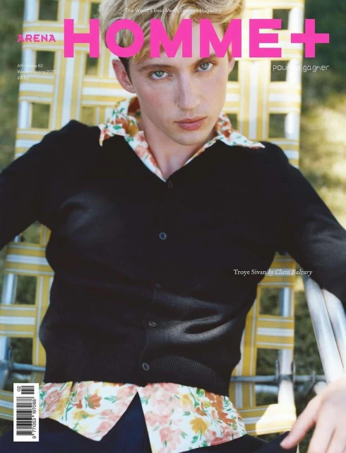 Magazine cover featuring Troye Sivan wearing a black cardigan and floral shirt, posing in a casual outdoor setting on a striped chair.