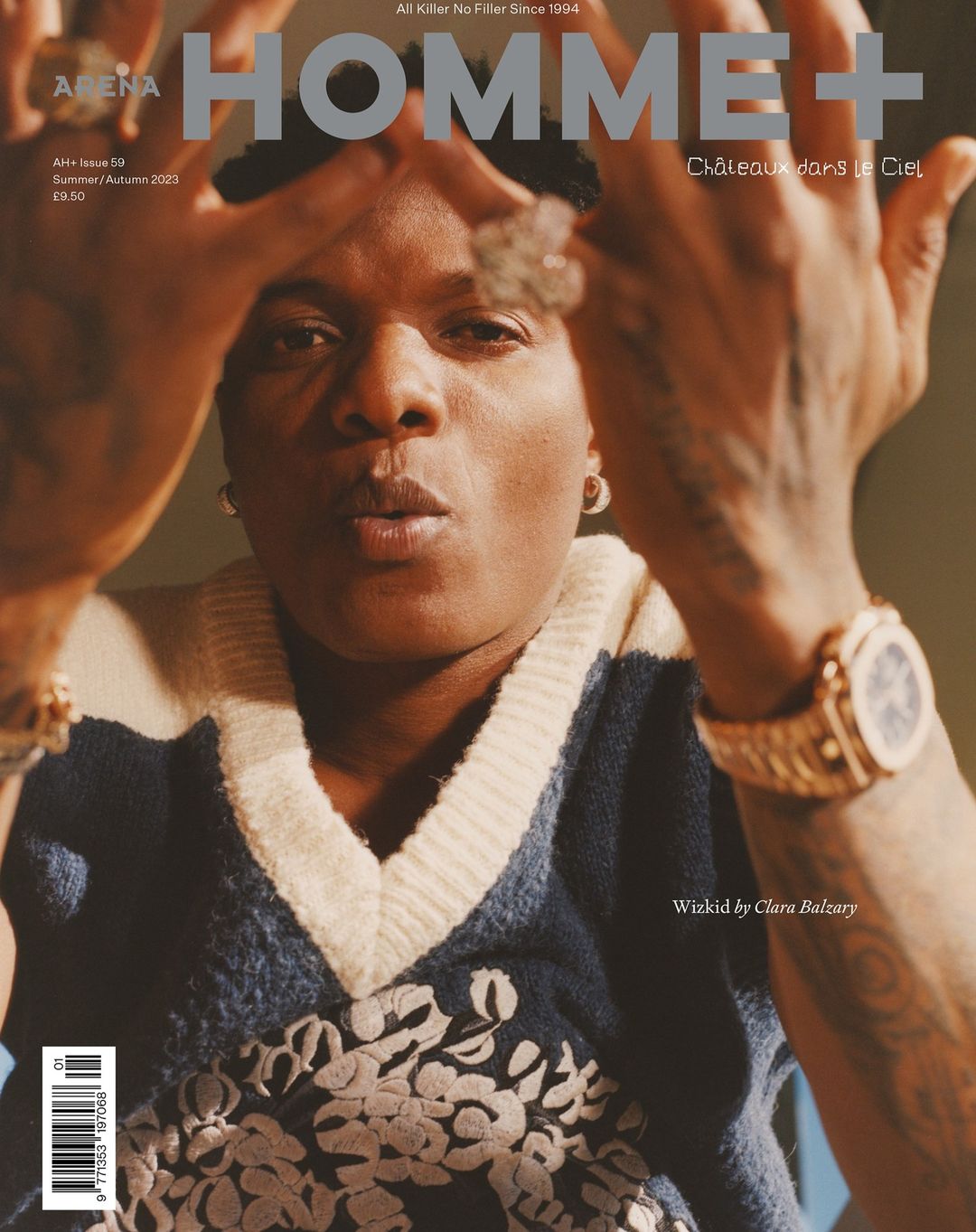 Magazine cover of Arena Homme+ featuring a portrait of a person wearing a patterned sweater, watch, and earrings with text overlay.