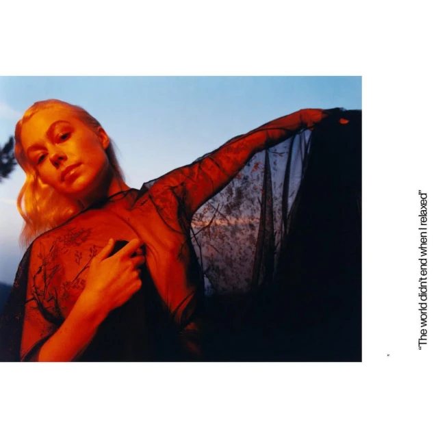 Portrait of a blond woman in a sheer black top, with a soft sky background, creating a dreamy and ethereal aesthetic.
