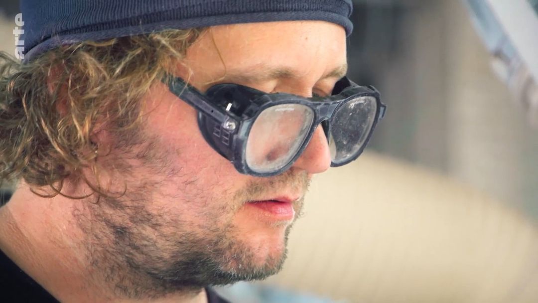 Close-up of adult male wearing protective eyewear and a cap, featuring a natural skin tone, captured with a shallow depth of field.