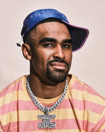 Portrait of a man wearing a blue cap, striped yellow and pink shirt, and a diamond chain necklace