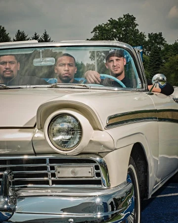 Three men sitting inside a vintage white convertible car, photographed by Clay Patrick Mcbride.