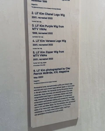 A display featuring information about Lil' Kim's wigs. The display is indoors and features a description of the wigs.