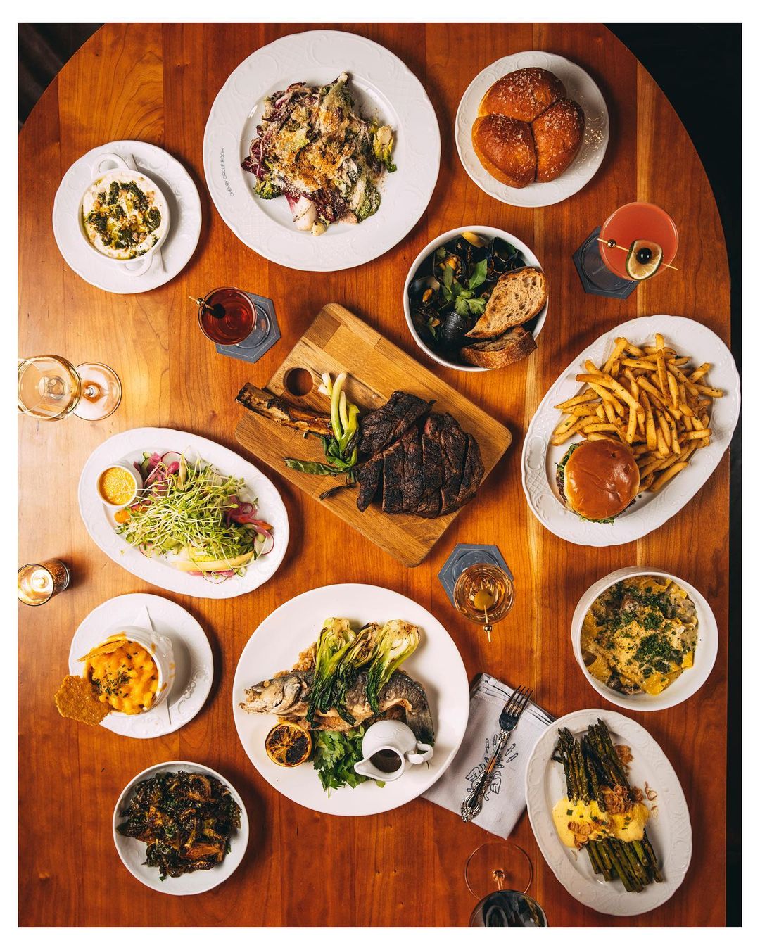 Overhead shot of a wooden table abundantly filled with various plates of gourmet food, showcasing a diverse culinary spread.