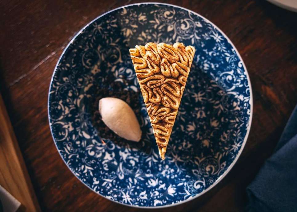 Overhead shot of a slice of cake resembling a brain served with a scoop of ice cream on a blue and white patterned plate.