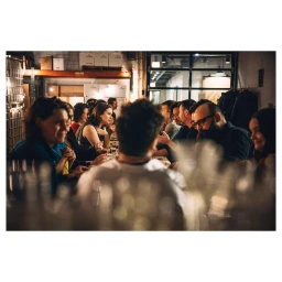 Group of people seated at a long dining table in a warehouse interior photographed by Clayton Hauck.