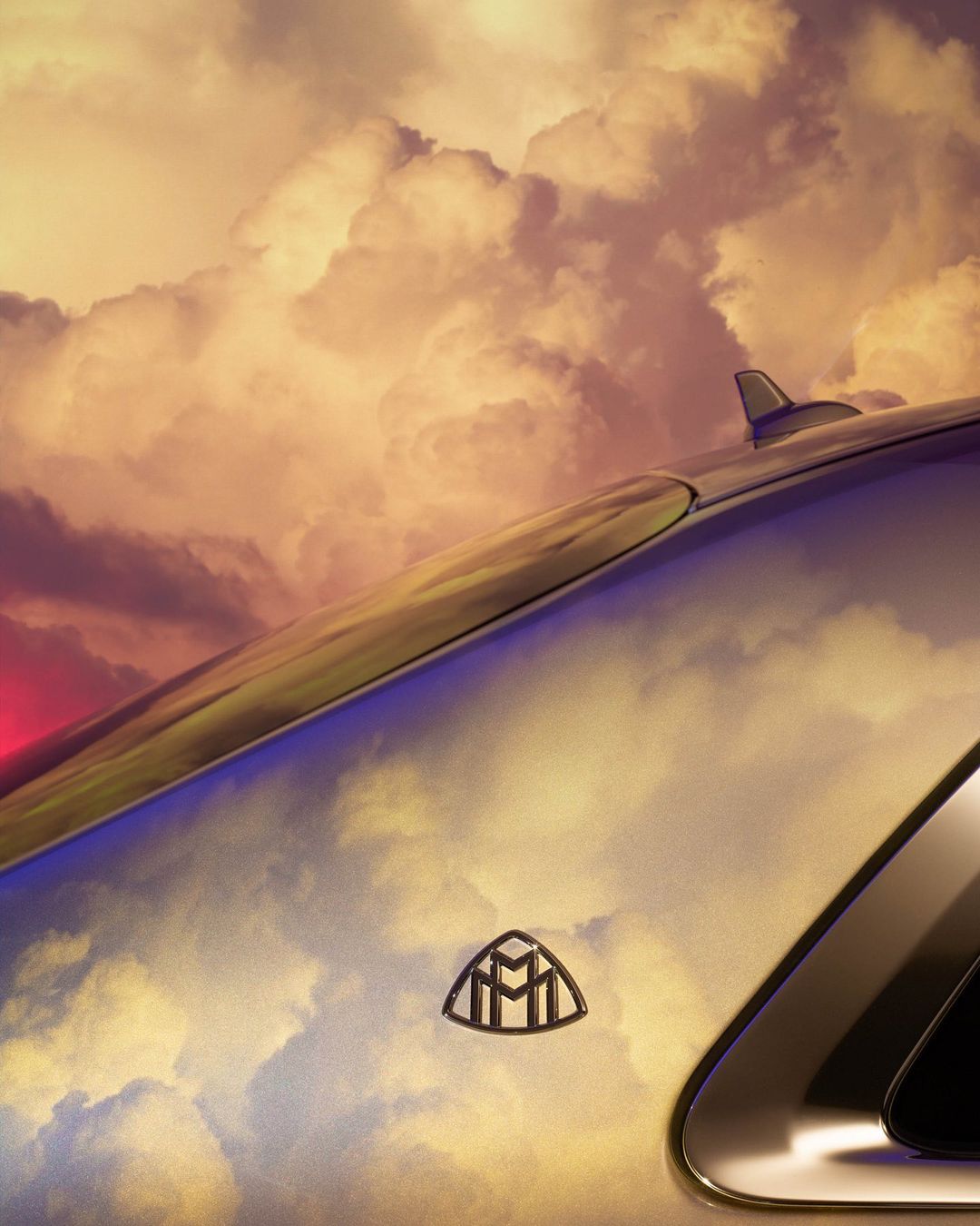 Close-up of a Maybach car's roofline against a backdrop of dramatic, colorful clouds, emphasizing luxury and automotive design.