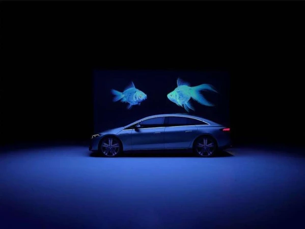 Sleek silver car showcased against a dark backdrop with ethereal blue fish illustrations floating above it in a captivating automotive display.