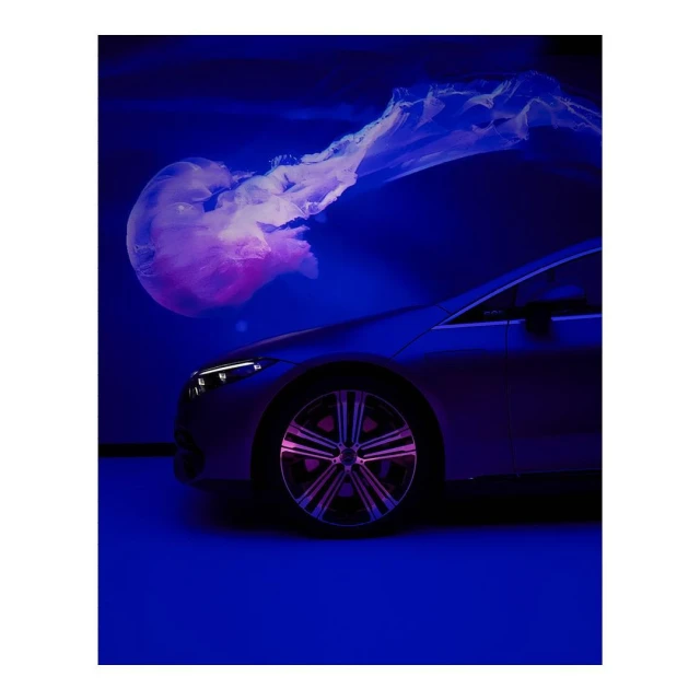 Silver car interior studio shot with ambient blue lighting illuminating the vehicle's sleek design and chrome wheel rims.