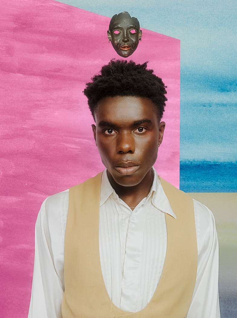 Portrait of a Black male model wearing a vest in front of a modern watercolor backdrop with pink and blue hues, with a mask above his head.
