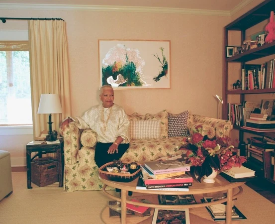 Elderly woman seated on a patterned sofa in a living room photographed by Clifford Prince King