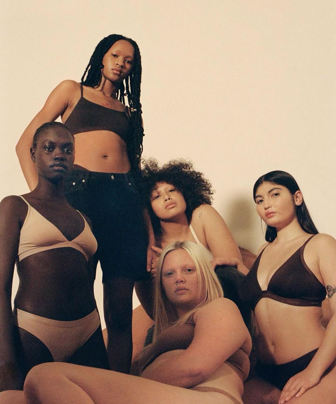 Group of five diverse female models posing together in underwear against a plain studio backdrop captured by Clifford Prince King