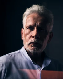 Portrait of an elderly man with white hair wearing a light blue button-down shirt under dramatic low-key lighting by Lukasz Rajchert