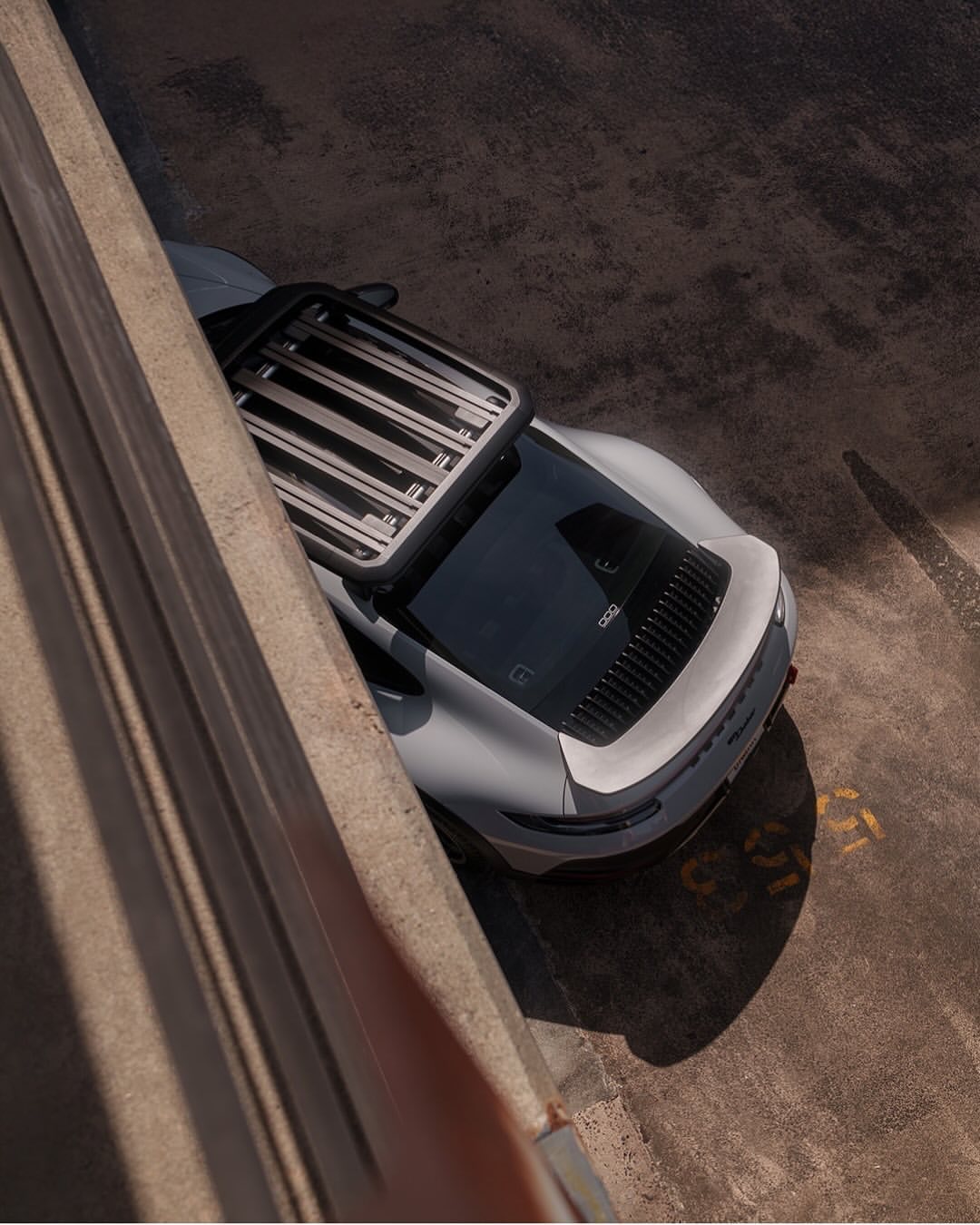 High-angle shot of a gray electric vehicle parked indoors, featuring a luggage rack and facing the camera.