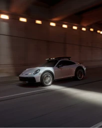 White sports car driving inside an underground tunnel with warm overhead lighting by Clint Davis