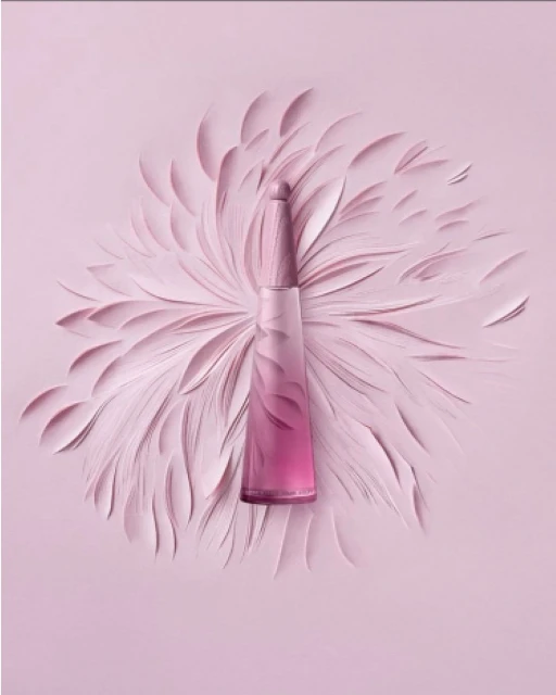 Perfume bottle on pastel pink backdrop with abstract feather-like shapes, creating a visually appealing and monochromatic presentation.