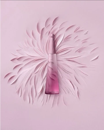 Perfume bottle on pastel pink backdrop with abstract feather-like shapes, creating a visually appealing and monochromatic presentation.