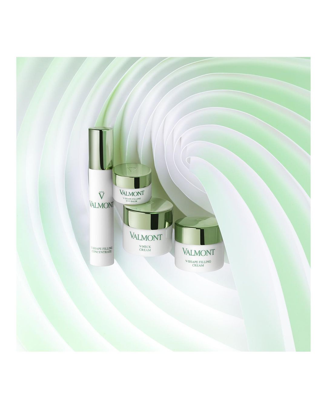 Valmont skincare product line arranged against a soft, swirling white and green background, presented as a beauty advertisement.