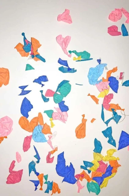 Colorful crumpled tissue paper scattered on a white surface, creating an abstract and textured design with blue, pink, yellow, and orange hues.
