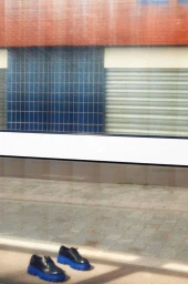 A pair of black chunky platform shoes with bright blue soles resting on concrete sidewalk.