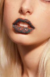 Extreme close-up of lips adorned with teal beads and orange gloss, with fair skin and blonde hair