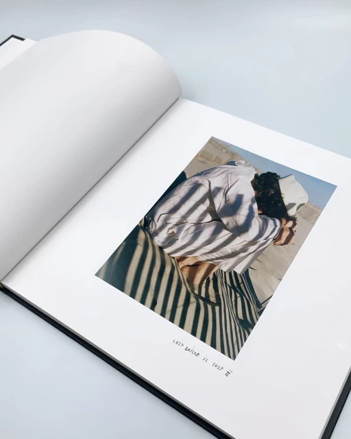 Open book features a photograph of a person in a sandy outdoor landscape. The photograph is marked with shadows and has stylized text.