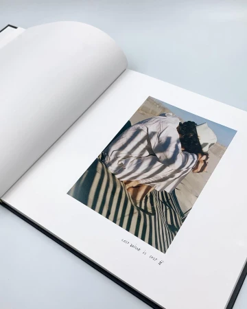 Open book features a photograph of a person in a sandy outdoor landscape. The photograph is marked with shadows and has stylized text.