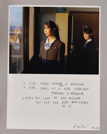 Two young Asian women in school uniforms are depicted in an indoor scene, one looking out a window, with text overlaid on the photograph.
