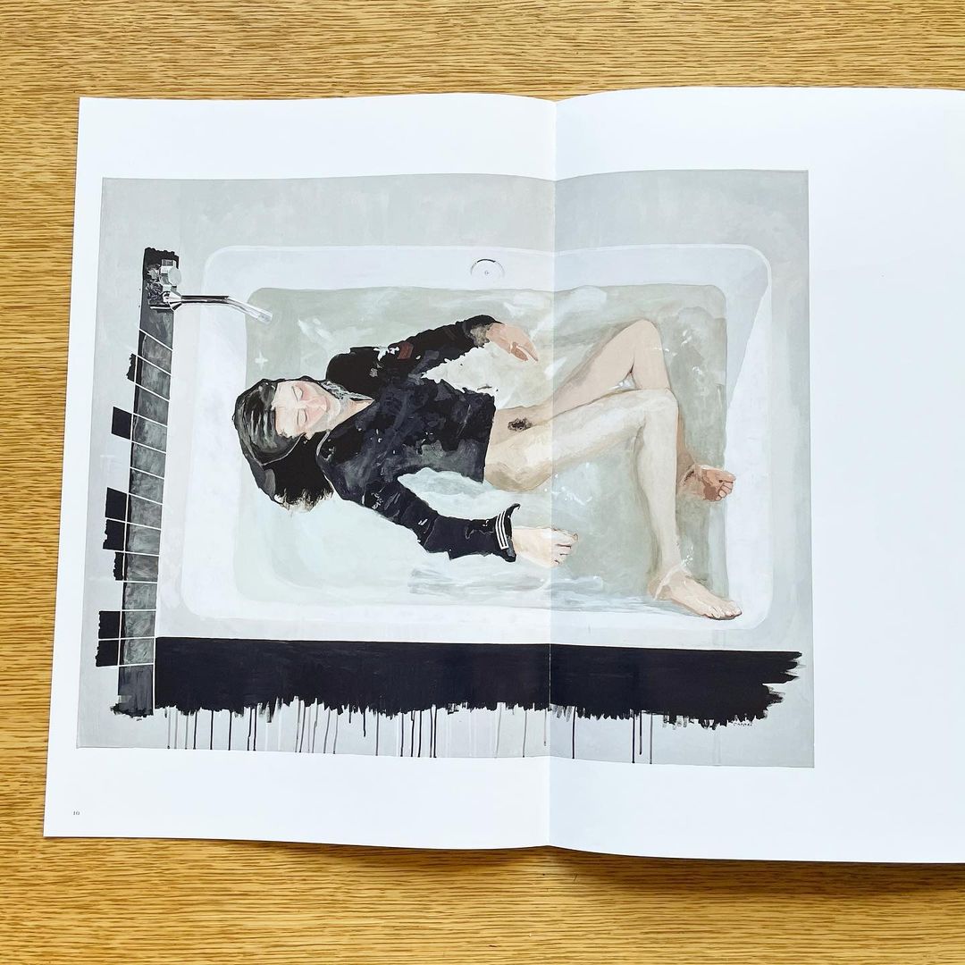 Artistic image in a magazine featuring a woman in a bathtub with stylized monochrome elements creating a unique visual composition.
